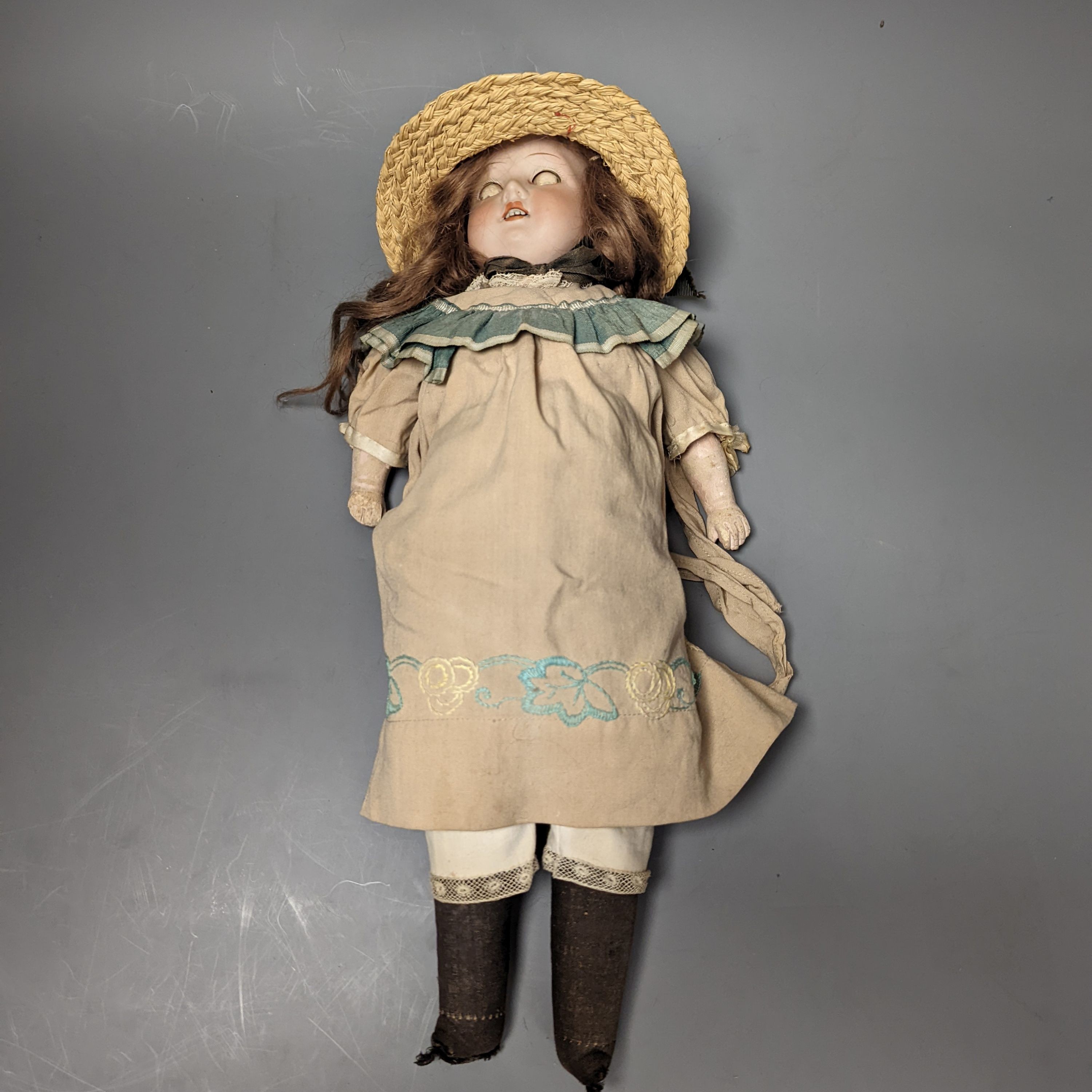 An Armand Marseille 370 bisque headed doll, wearing a basket weave boater and brown embroidered dress, 44cms high.